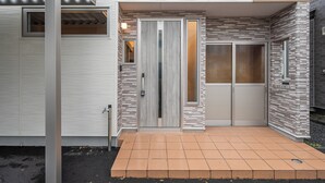 A modern building entrance with a metal door, a small window, and a tiled entrance area. - CALM FOREST (Asahikawa)