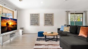Ein modernes Wohnzimmer mit Flachbildfernseher, einer Couch, einem Couchtisch und zwei abstrakten Wandbildern.