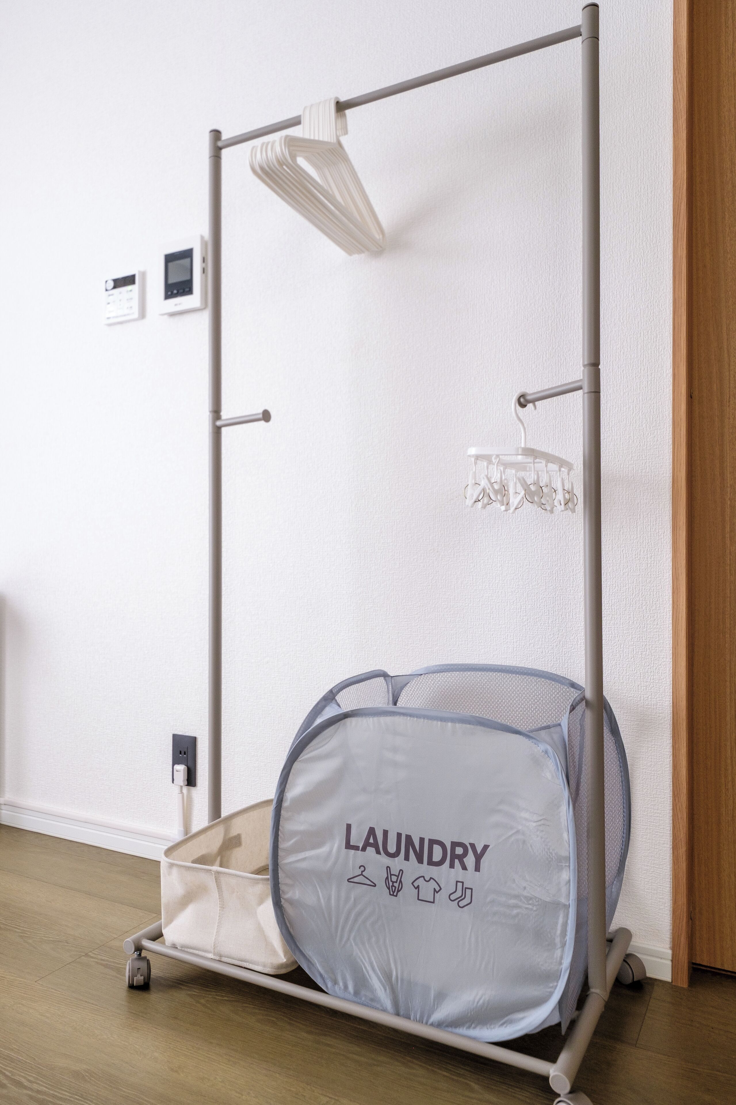 Un chariot à linge portable doté d’un sac en filet étiqueté « LINGE » et d’une tringle à suspendre.