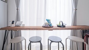 Una mesa de madera con un control remoto, un calendario y una planta pequeña. Hay tres taburetes frente a la mesa.