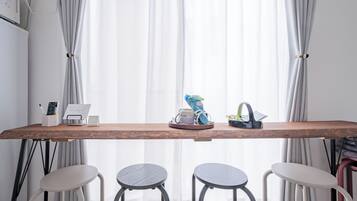 A wooden table with a remote control, a calendar, and a small plant. There are three stools in front of the table.