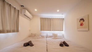 Habitación doble con dos camas, una ventana con cortinas, un equipo de aire acondicionado y un cuadro en la pared.