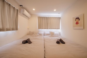 A double room with two beds, a window with curtains, an air conditioning unit, and a framed picture on the wall. - Asakusa25m｜TDL 37m｜Free Parking｜ 61㎡｜ 2BR｜up to 9 (葛飾区新宿5丁目)