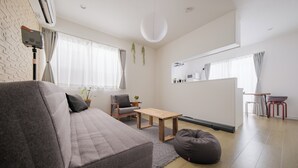 Una sala moderna con un sofá gris, una mesa de centro de madera y un sillón informal.