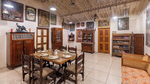 Un comedor con una mesa y sillas de madera, rodeado de armarios y estanterías llenas de libros y objetos decorativos.
