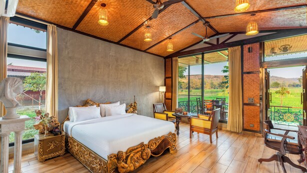Un dormitorio amplio con una cama grande, un escritorio y vistas a un paisaje exuberante.