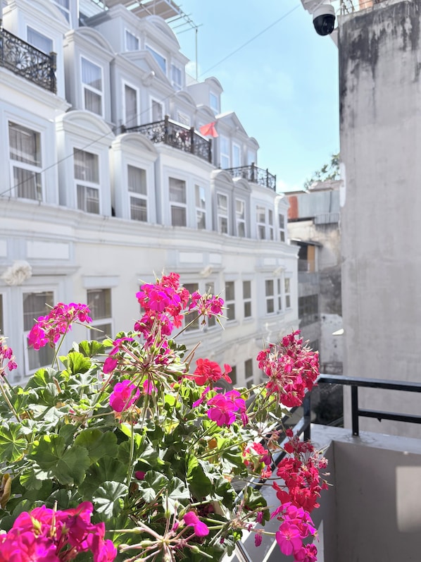 Un balcón con flores rosas y vistas a edificios blancos.