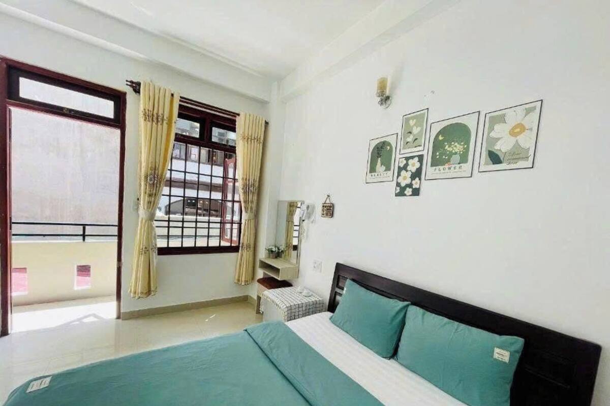 A bedroom with a bed, curtains, a window, and wall art.