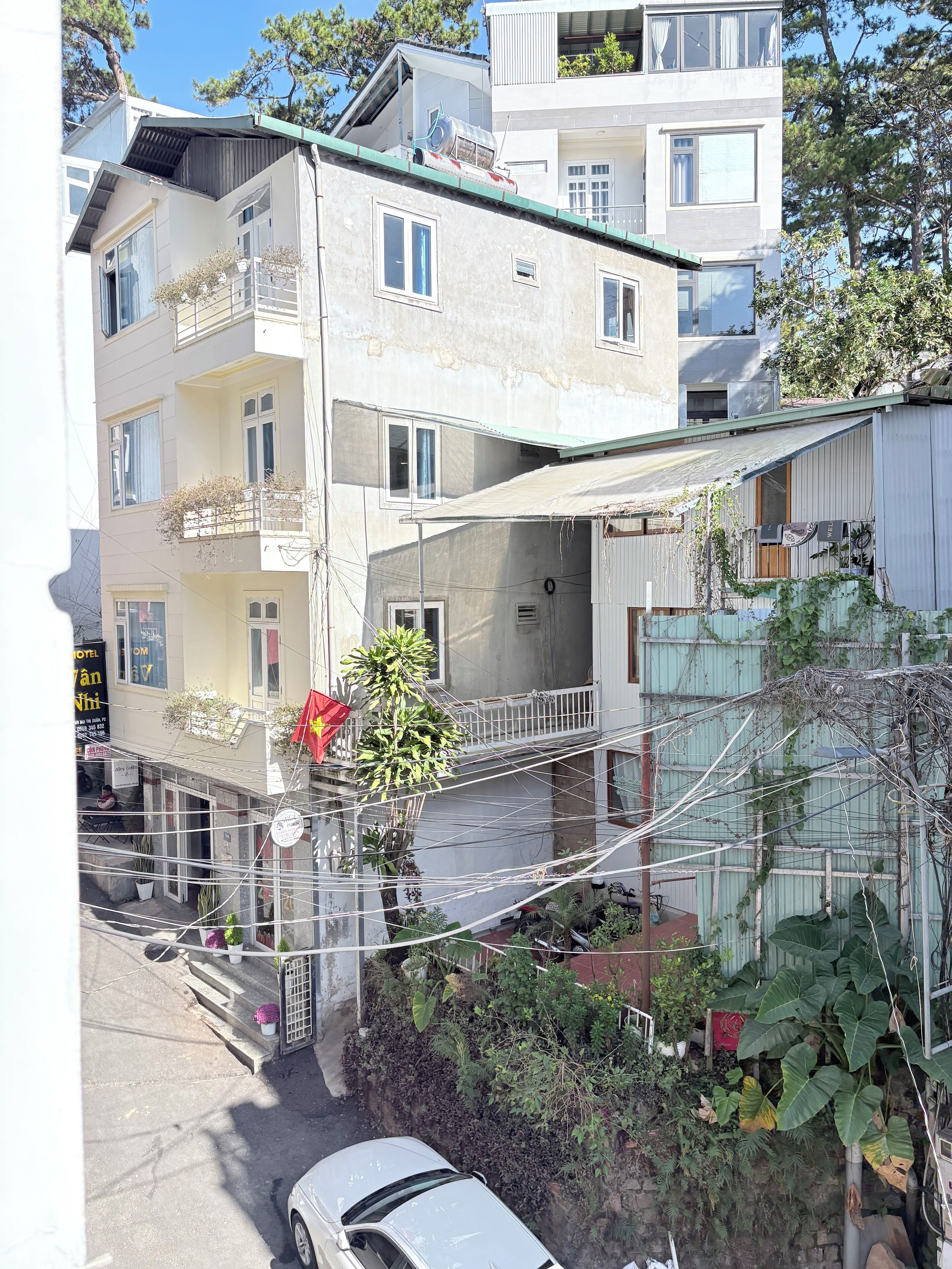 Un edificio de varios pisos con balcones, una entrada visible y un coche aparcado.
