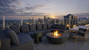 Eine Dachterrasse mit Feuerstelle, Sitzgelegenheit und Blick auf den Stadtpanoramablick.
