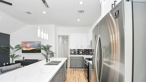 A modern kitchen with a large island, stainless steel appliances, and a minimalist design. - Modern 3 Bedroom Close To DTWN/NRG/Med Center (Houston)