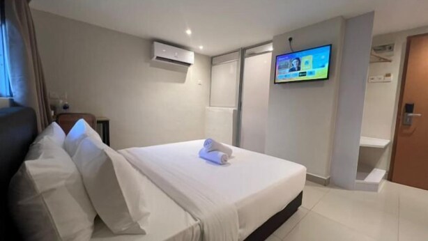 A hotel room with a bed, a TV mounted on the wall, and an air conditioning unit. - Swing & Pillows @ Kajang Selangor (Kajang)