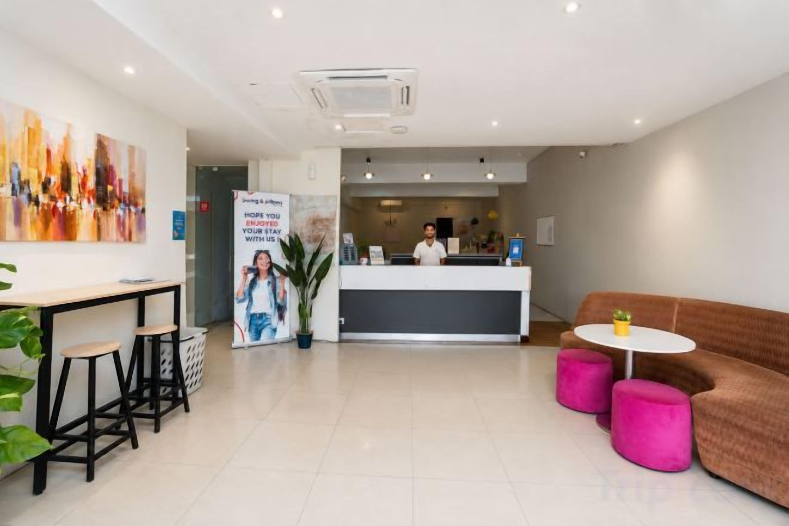Zona de recepción de un hotel con mostrador, asientos y escritorio.