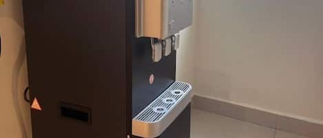 Egy vízautomata, amely vezérlőpanellel és ablakra néző kilátással rendelkezik.