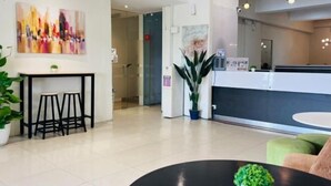 A modern hotel lobby with a reception desk, a seating area with stools, and a large abstract painting on the wall. - Swing & Pillows @ Kajang Selangor (Kajang)