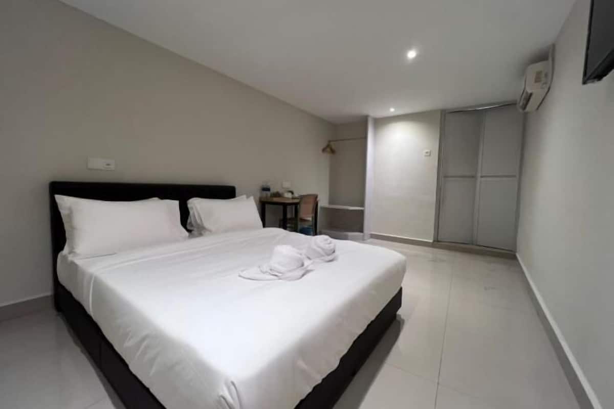 A hotel room with a bed, a small table, and a wardrobe.