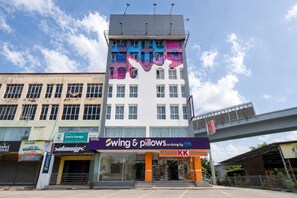 Ein mehrstöckiges Gebäude mit einer auffälligen Schilder für 'Swing & Pillows.co.living by HILLTOP' im Erdgeschoss.