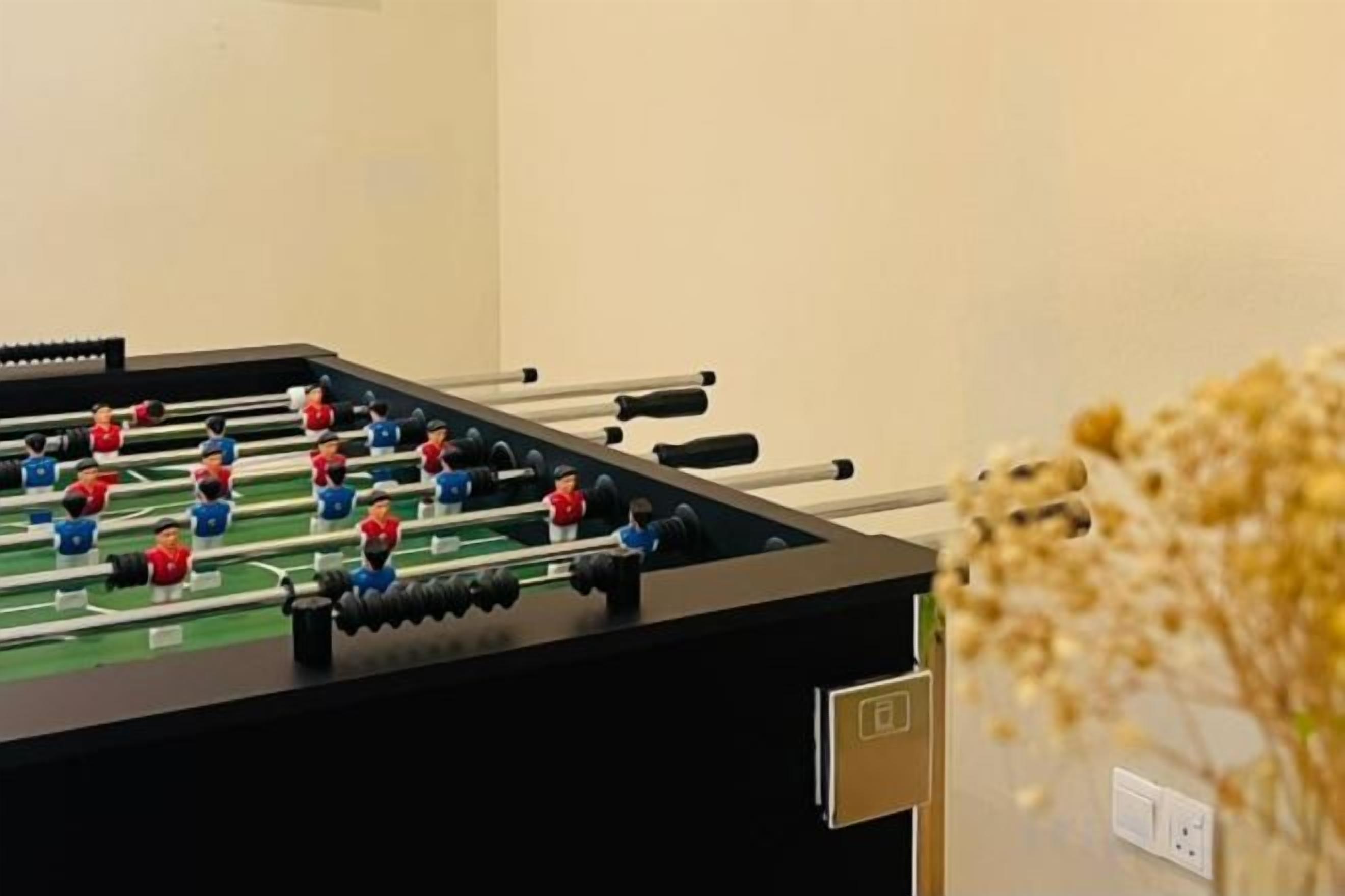 A foosball table in a room with a plain wall and a power outlet.