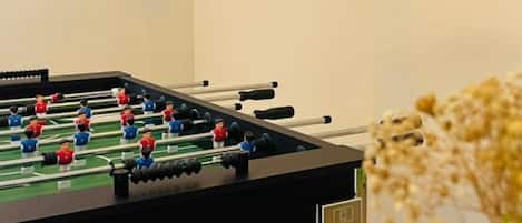 A foosball table in a room with a plain wall and a power outlet.