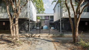 Un cortile recintato con alberi, un vialetto e un edificio con un balcone.