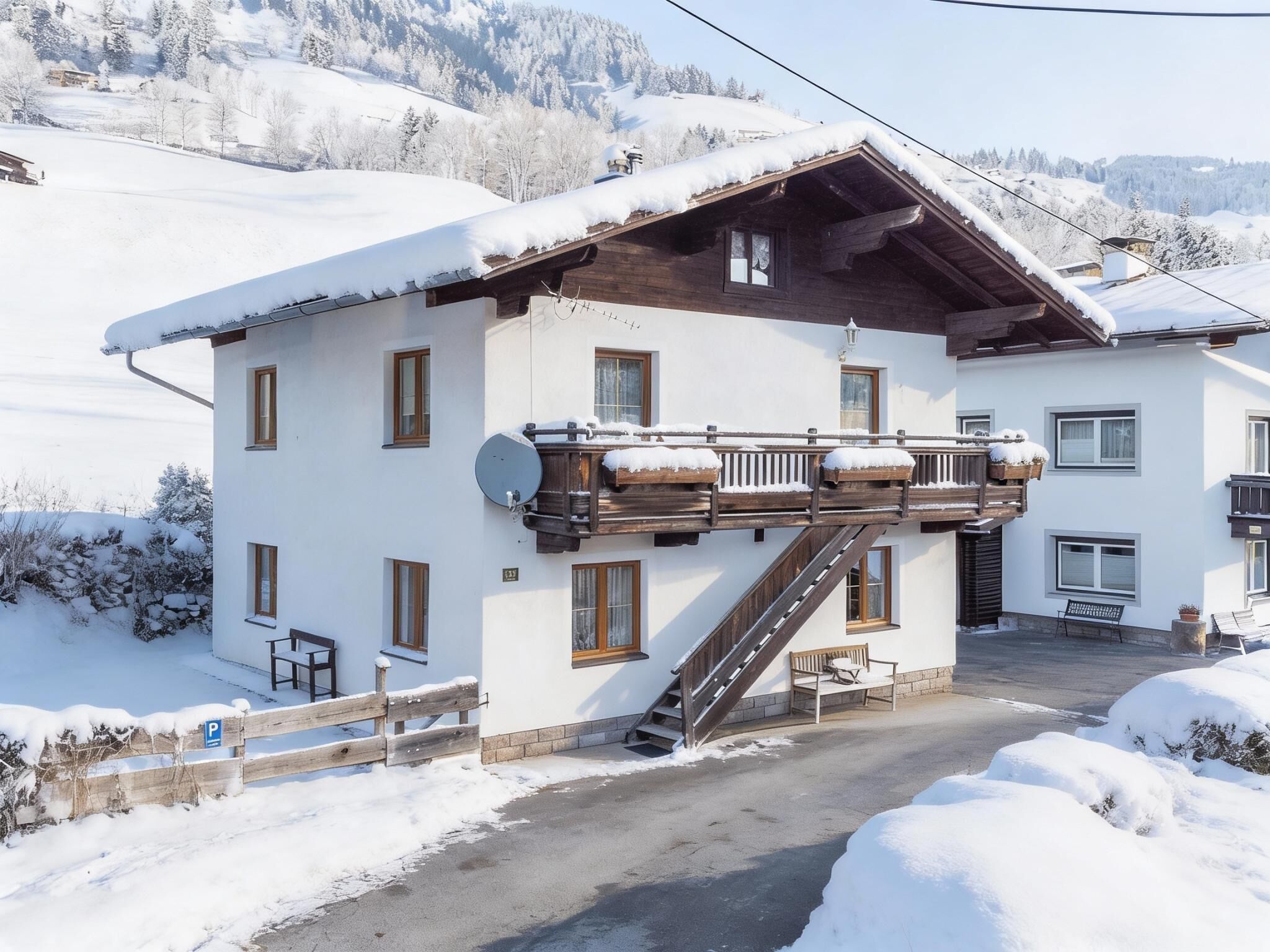 Eine zweistöckige Chalet mit Holzbalkon, einer Skiseilbahn und freiem Blick auf die verschneite Landschaft.