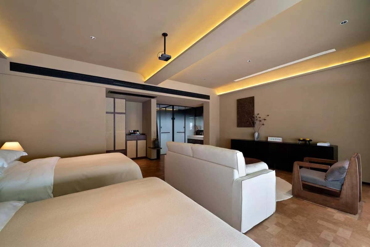 Een moderne hotelkamer met twee bedden, een bank, een stoel en een bureau.