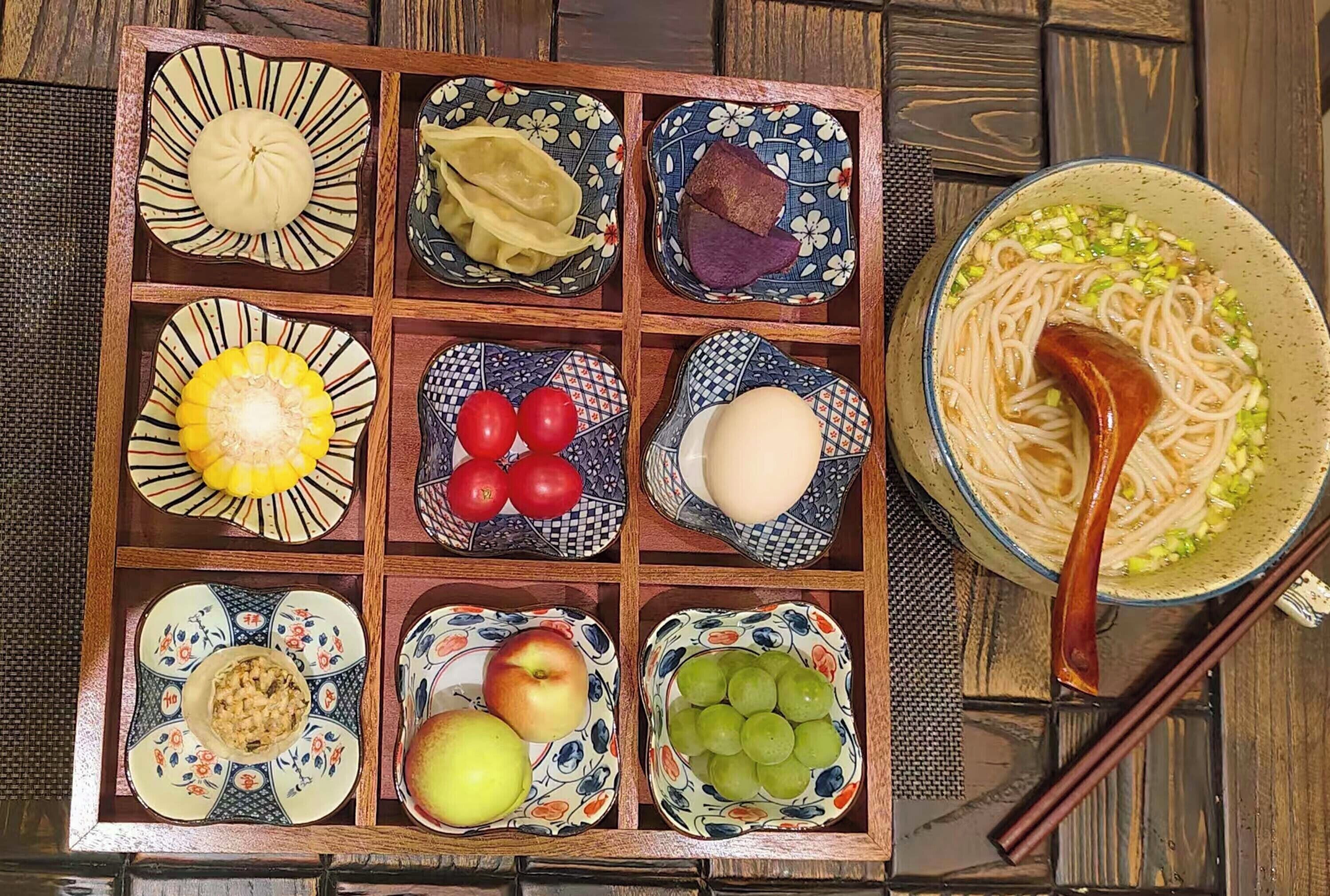 Una tradizionale scatola bento giapponese con diversi cibi e una ciotola di noodles.