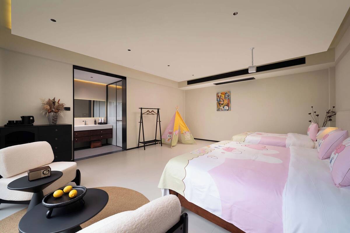 Een moderne slaapkamer met een bed, een bank, een klein tafeltje met citroenen en een bureau met een lamp.