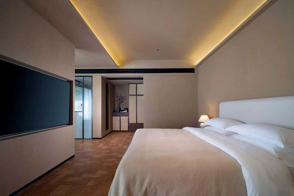 Een moderne hotelkamer met een groot bed, een flatscreen-tv en een klein bureau.