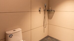 Un baño pequeño y moderno con inodoro, ducha y repisa con artículos de aseo.