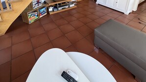 A living room with a wooden staircase, a television, a cabinet, and a couch. - Detached house for sole use - first floor exclusively for 2 people (Dornum)