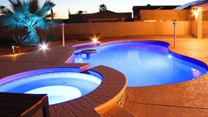 A swimming pool with a curved design, surrounded by a brick deck and palm trees. - Private Pool, Spa! Updated Home Near London Bridge (Lake Havasu City)