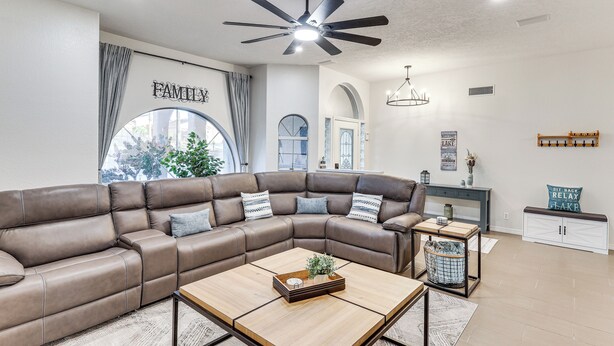 A modern living room with a sectional sofa, a coffee table, and a ceiling fan. - Private Pool, Spa! Updated Home Near London Bridge (Lake Havasu City)