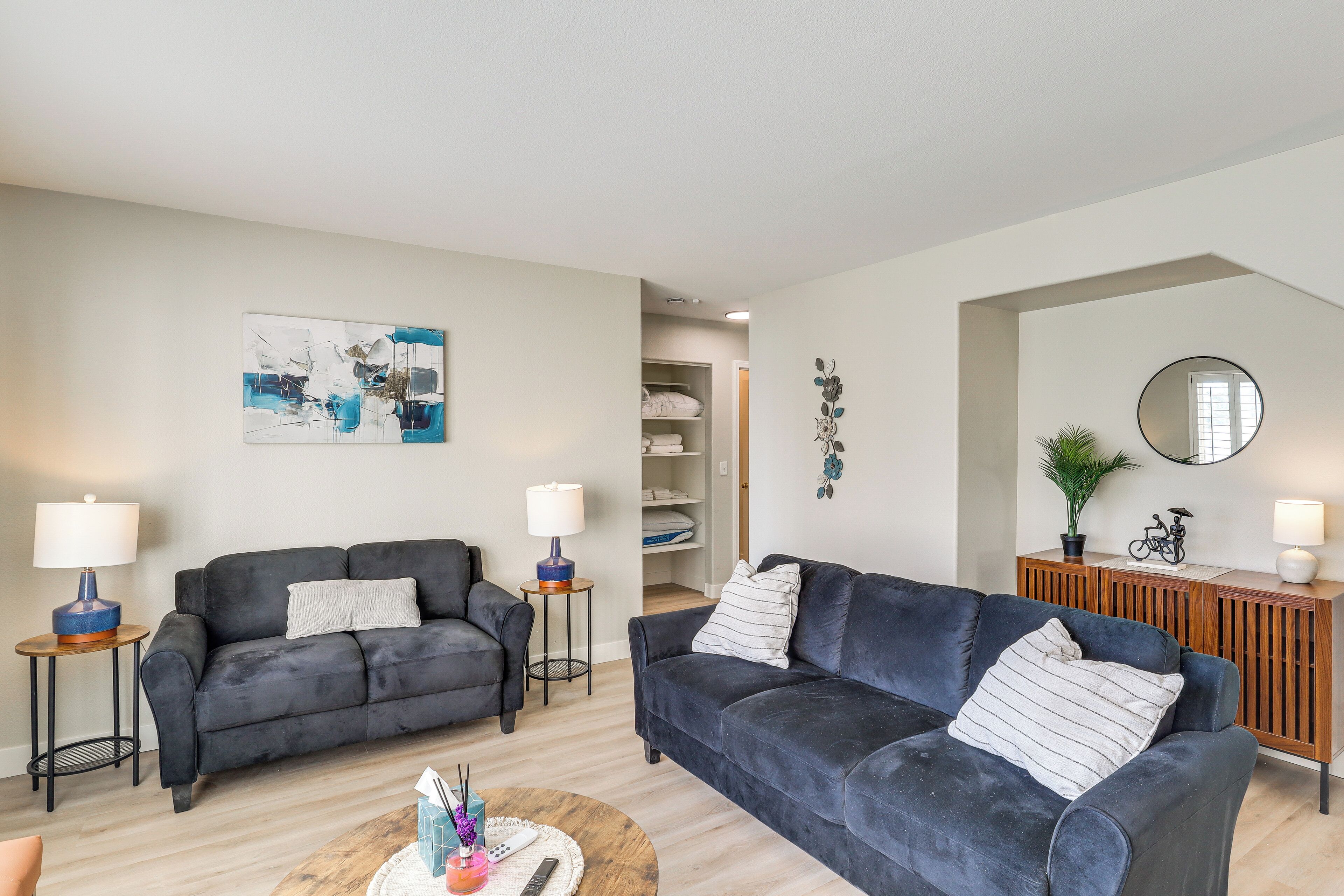 Ein modernes Wohnzimmer mit zwei dunklen Sofas, einem Couchtisch und einer Holzkommode.