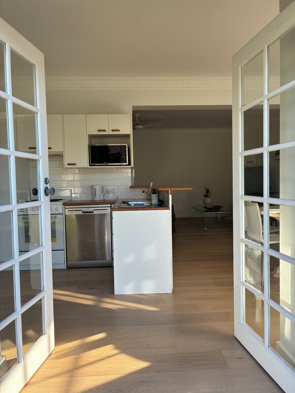 Une cuisine moderne avec des meubles blancs, un four à micro-ondes, un lave-vaisselle et un plan de travail en bois.