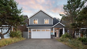 Una casa a due piani con un garage, immersa nel verde e con vialetto privato.