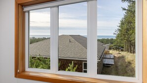 Una ventana con vista a una casa de techo inclinado y terraza de madera.