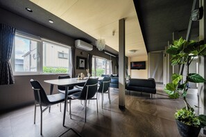 A modern interior with a dining area, seating, and a mounted television. - THE LAVENRIDGE (Nakafurano)