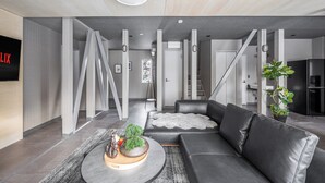 A modern living room with a grey sofa, a coffee table with decorative items, and a large plant. - THE LAVENRIDGE (Nakafurano)