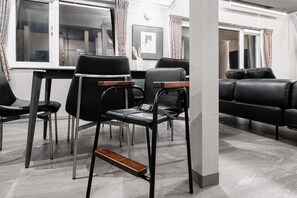 A modern living room with a black leather sofa, a dining table with chairs, and a decorative white rabbit sculpture. - THE LAVENRIDGE (Nakafurano)