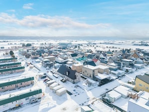 A snow-covered residential area with multiple houses and buildings, including a large industrial facility.