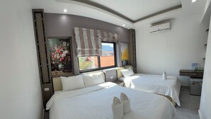 A hotel room with two beds, a small desk, and a window with a view of the outside. - VangVieng Boutique Hotel (Vang Vieng)