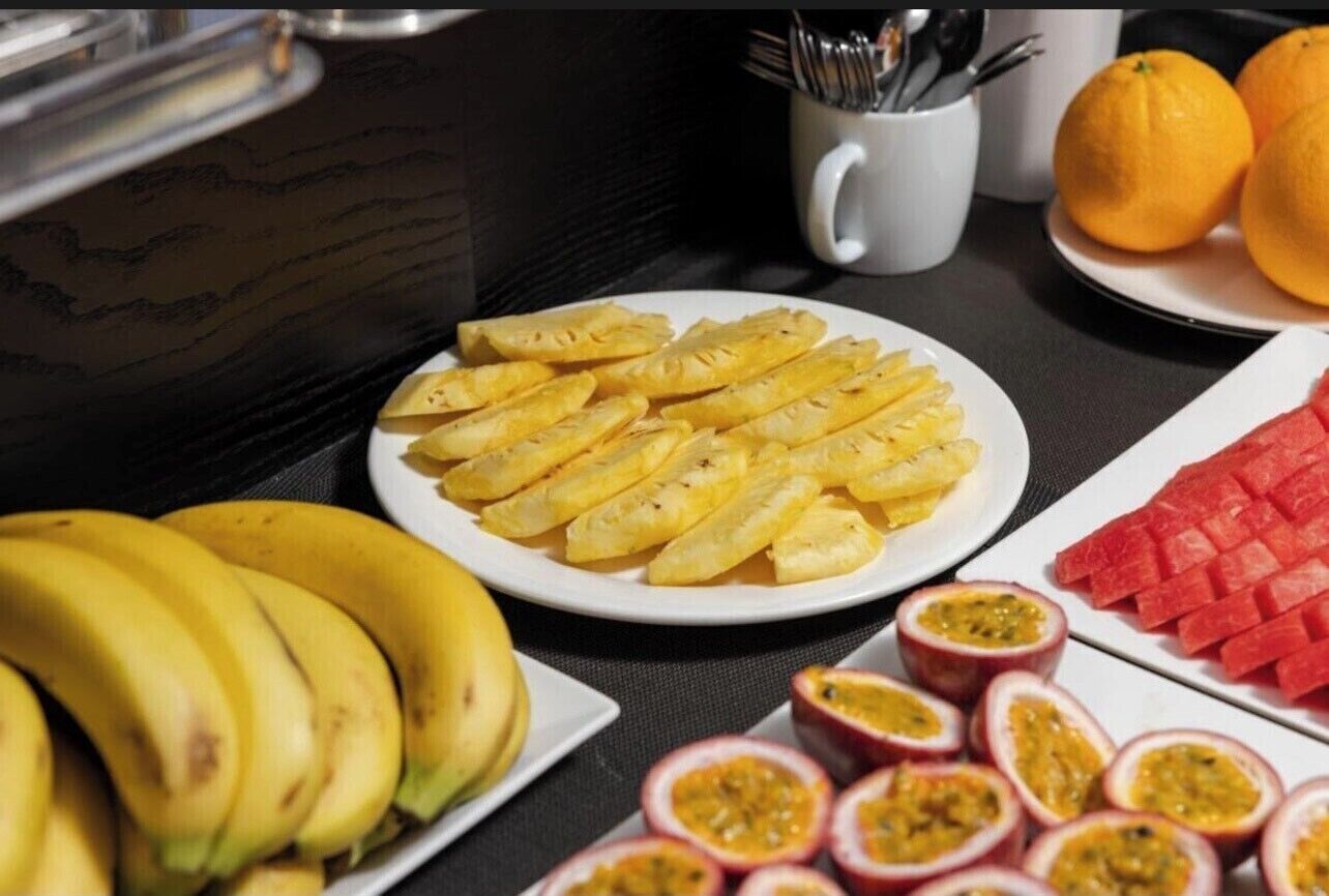 A breakfast buffet with sliced fruits and a plate of bananas.