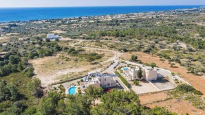 An aerial view of Villa Pheobe Gennadi with a swimming pool, surrounded by greenery and a coastal landscape. - Villa Phoebe Gennadi (2W76+JJ South Rhodes, Greece)