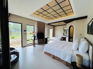 Un dormitorio amplio con una cama grande, televisor de pantalla plana, bañera y vistas al exterior.