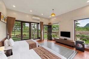 Una camera d'albergo con un letto grande, una TV e vista sull'esterno.