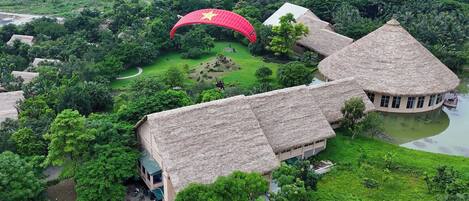 A thatched-roof building with a circular courtyard and a large red flag.