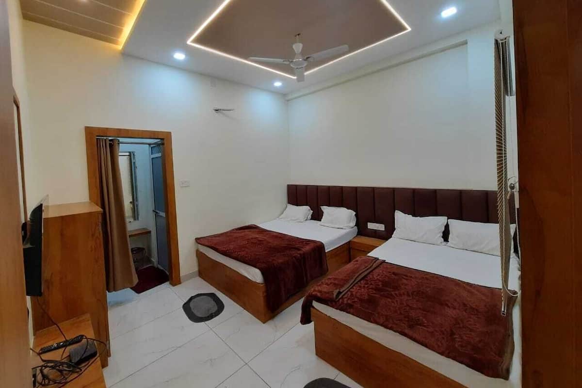 Una habitación de hotel con dos camas, un ventilador de techo y un armario de madera.