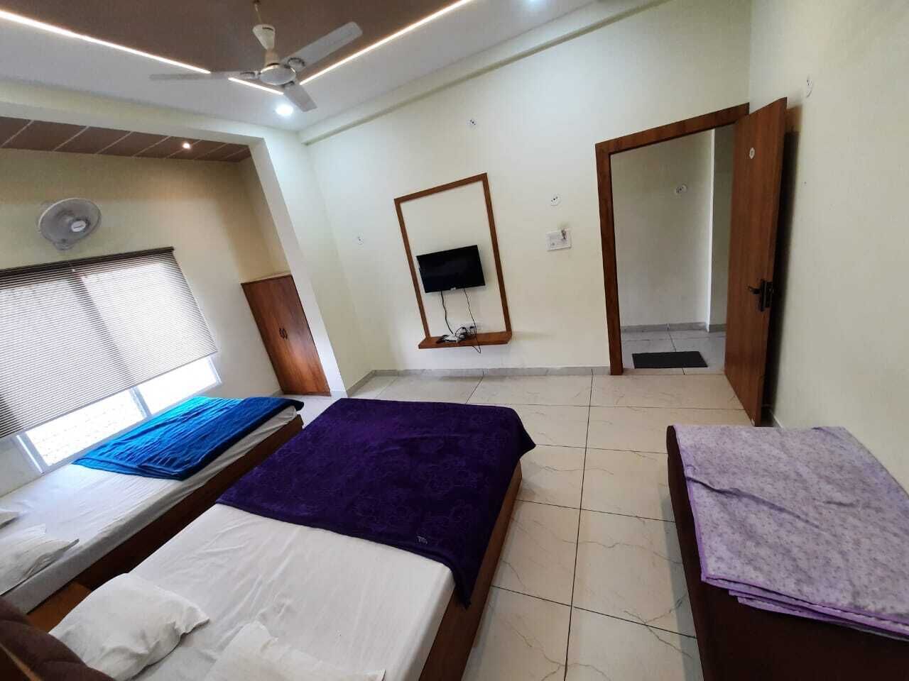 A bedroom with two beds, a TV, a ceiling fan, and a door.