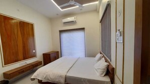 Une chambre à coucher avec un lit, une armoire en bois, un bureau et une fenêtre avec des stores.